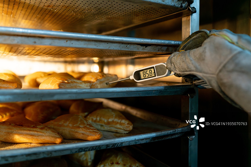 面包师在烤箱里检查一些糕点的温度图片素材
