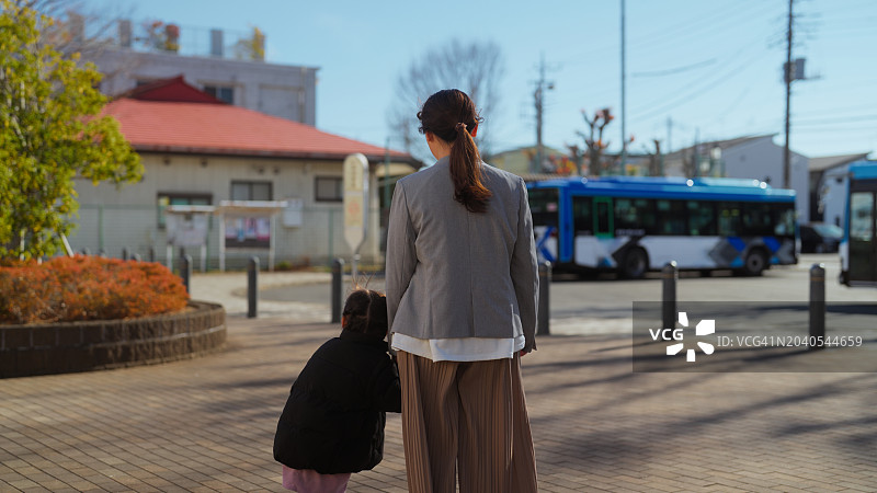 一位女商人带着她的小女儿在公交车站上下班图片素材