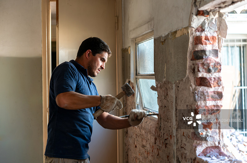 建筑工地上的拉丁美洲蓝领工人用锤子和凿子从一户人家的房间里清除水泥图片素材