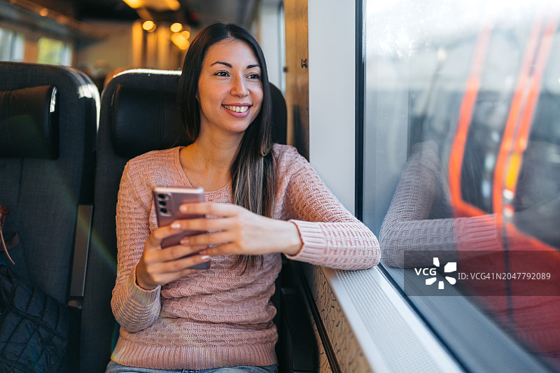 丹麦哥本哈根，一名年轻女子在火车上使用手机图片素材