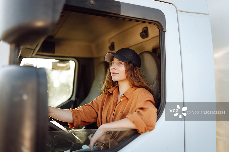 美丽的年轻女子的肖像专业卡车司机驾驶一辆大卡车。车内。图片素材