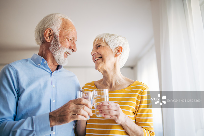 爱，年长的夫妇在厨房里喝一杯水，早上聊天或联系图片素材