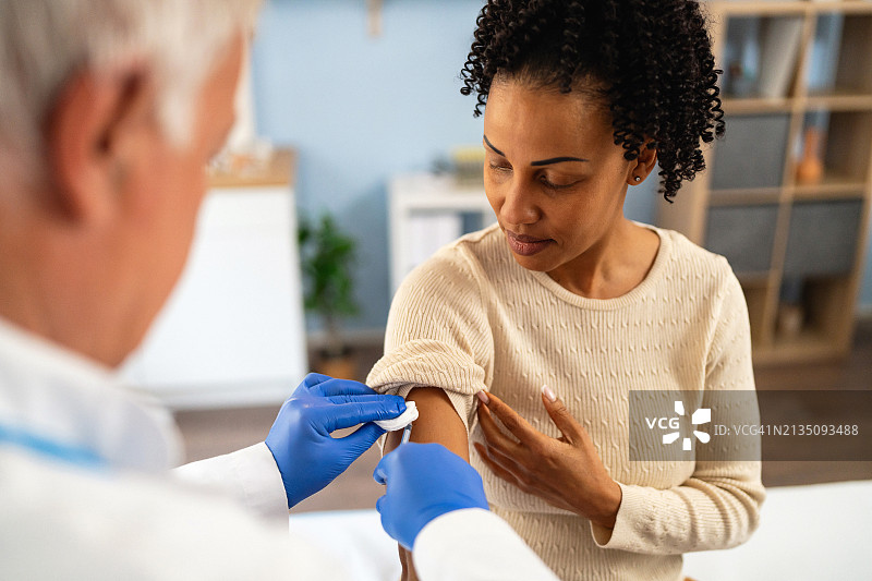 资深白种人男医生给一名非裔美国女病人注射流感疫苗图片素材