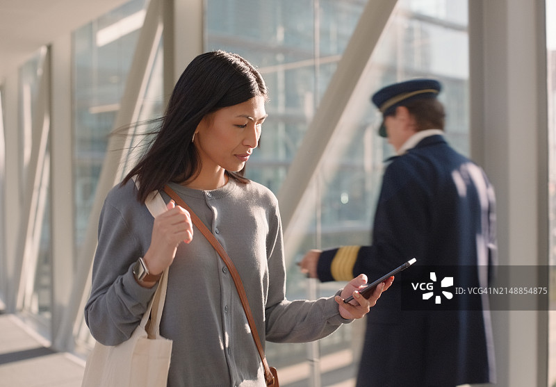 女士，在机场和智能手机上上网，因为时间紧迫而困惑于航班信息或技术问题。女性，丢失或沮丧的手机导航和搜索图片素材
