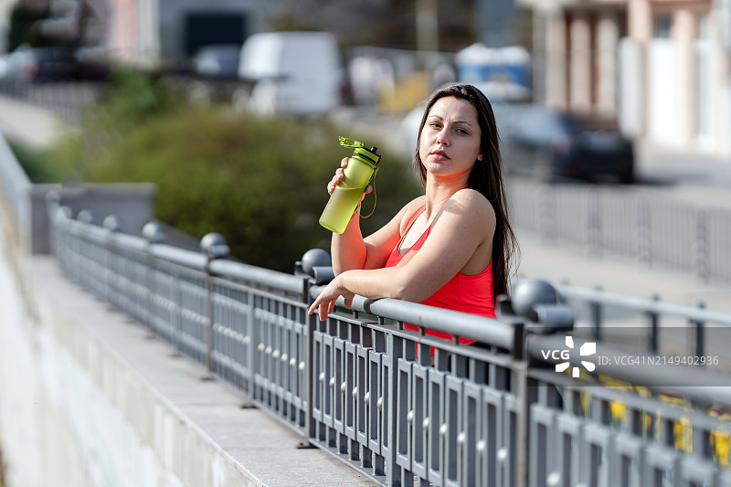 运动的年轻女子在城市里锻炼后喝水图片素材
