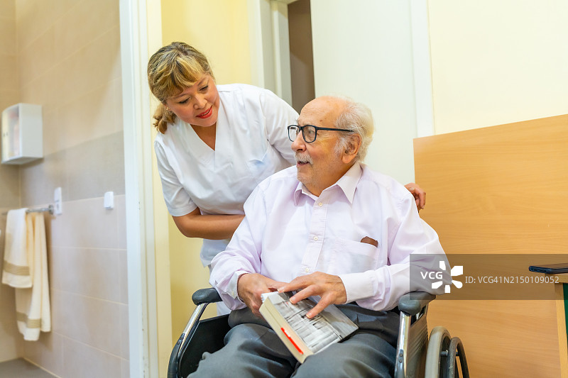 护士在老年科和一位快乐的老人交谈并帮助他图片素材