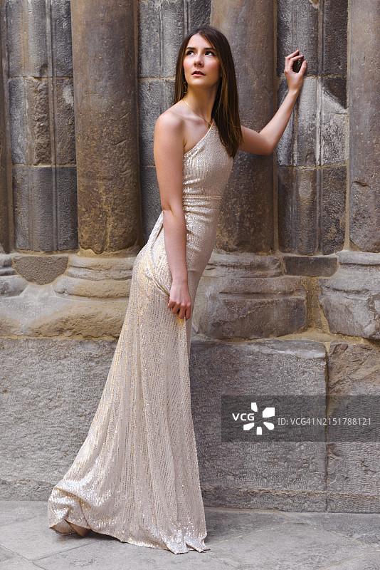 穿着优雅服装的年轻模特在大教堂的石柱上摆姿势图片素材