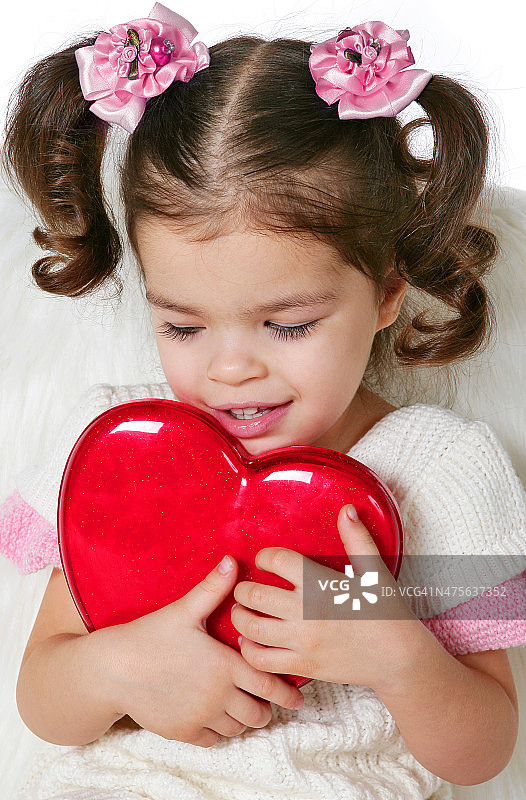 快乐的小女孩捧着一颗红心图片素材