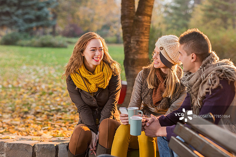 快乐的朋友在秋天的公园喝茶交流。图片素材