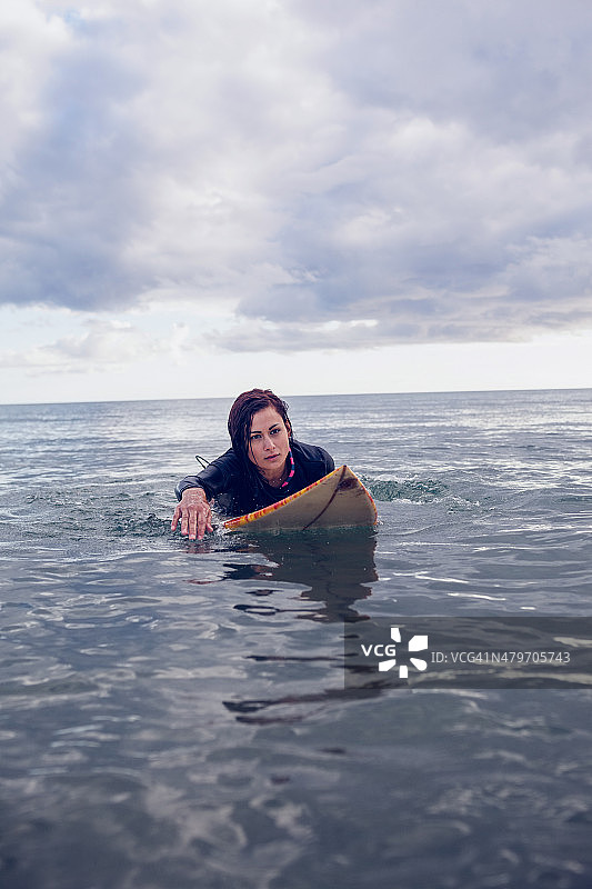 一个女人在水中冲浪板上游泳的肖像图片素材