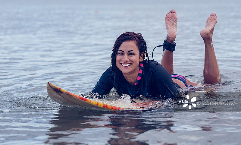 微笑的女人在水中冲浪板上游泳图片素材