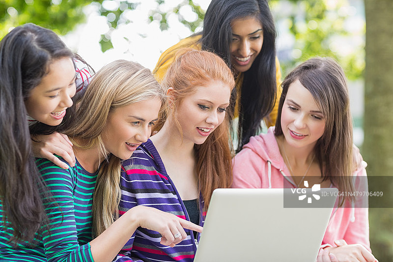 年轻的女大学生在公园里用笔记本电脑图片素材
