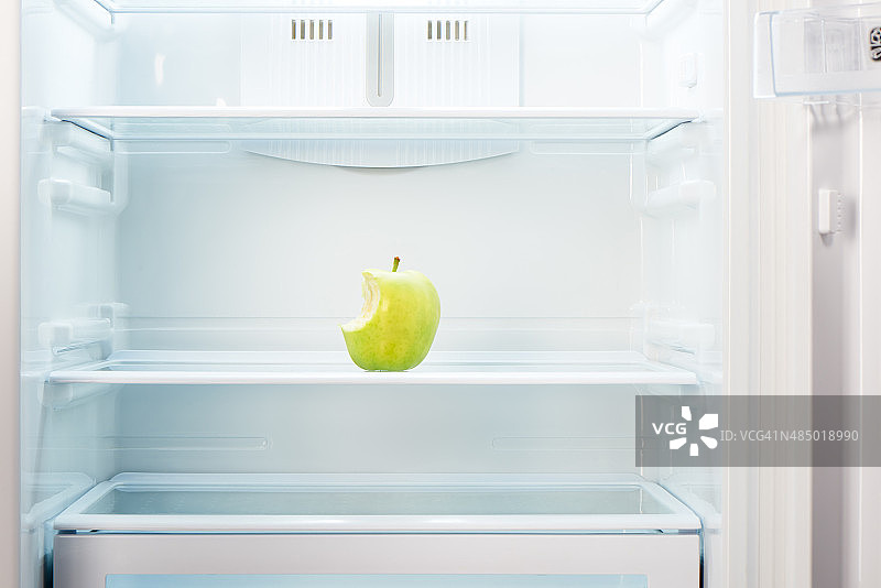 打开的空冰箱的架子上有被咬过的绿苹果图片素材