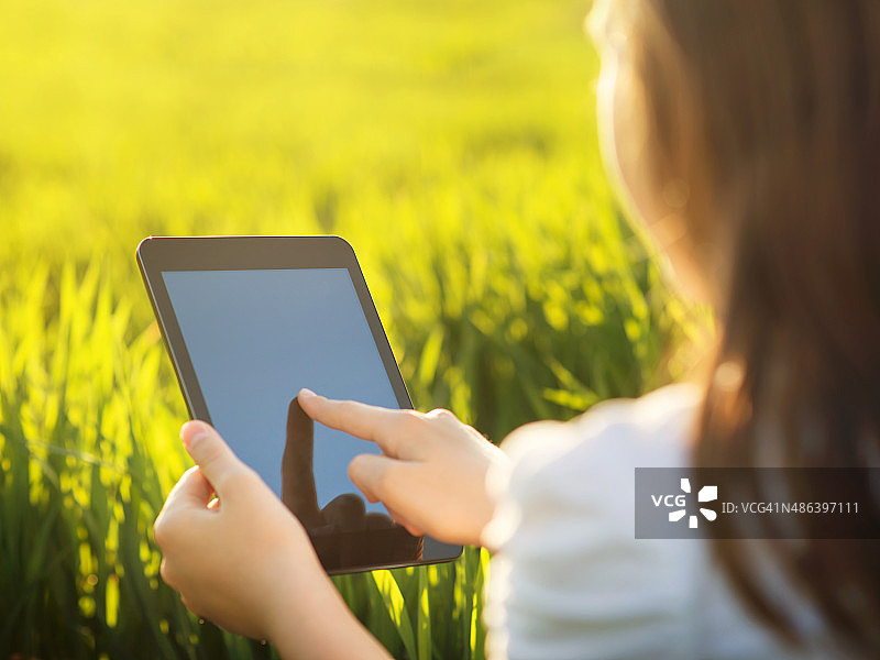 年轻女子在草地上用着平板电脑图片素材
