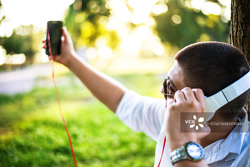 一个男人在公园里用智能手机听音乐图片素材