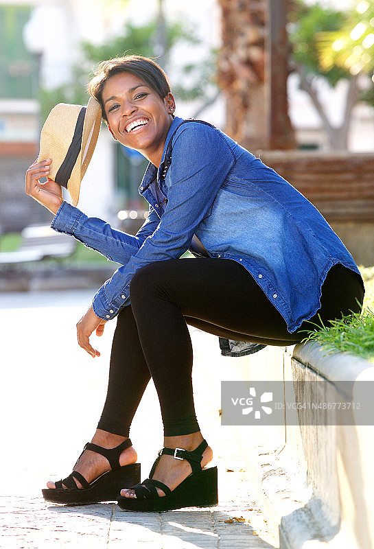 年轻的非洲裔美国人坐在外面微笑着图片素材
