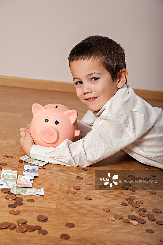 快乐的男孩，钱和他的小猪存钱罐图片素材