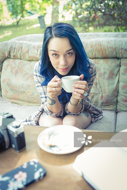 美丽的年轻女子纹身与蓝色的头发在户外生活方式图片素材