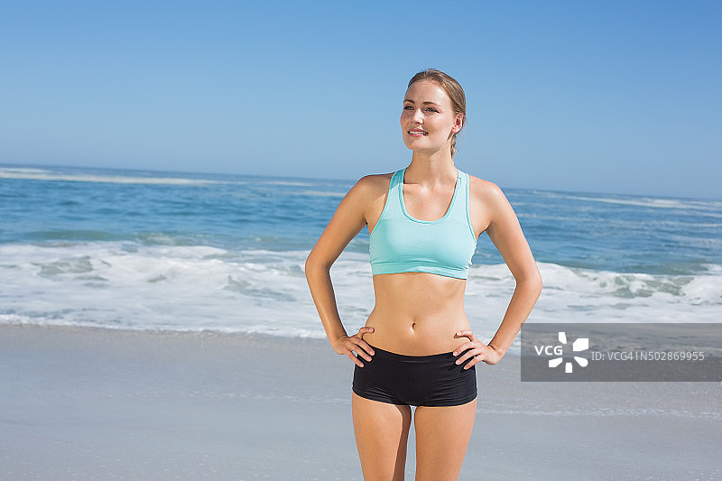 健康的女人双手叉腰站在沙滩上图片素材