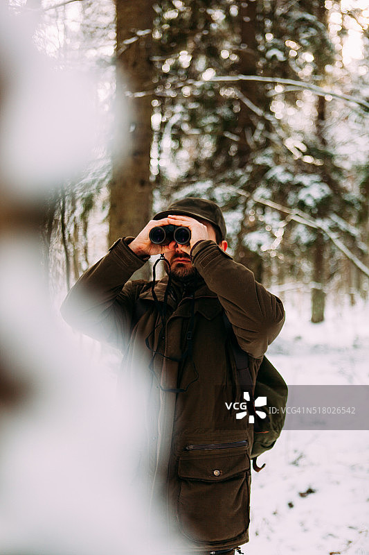 用双筒望远镜观察冬季森林的人图片素材