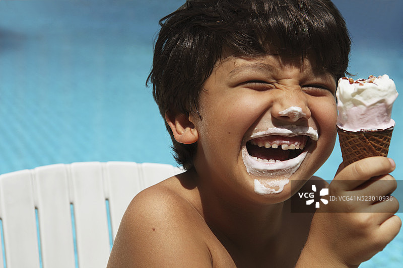 男孩(7-9岁)在游泳池边吃冰淇淋图片素材