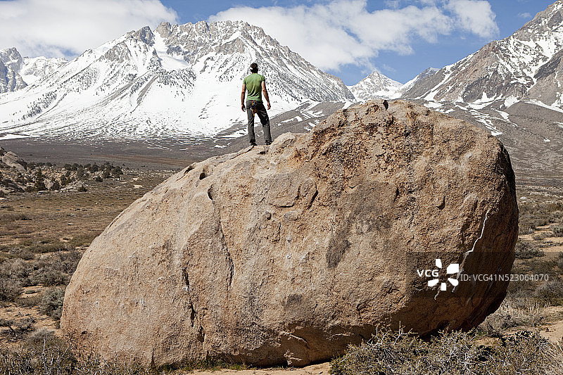 后视图的人站在巨石，面对雪山图片素材