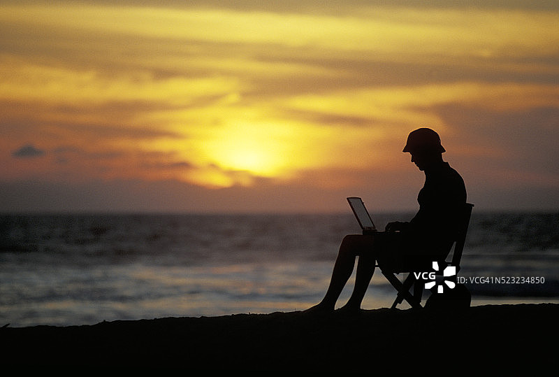 在海滩上用笔记本电脑的男人图片素材