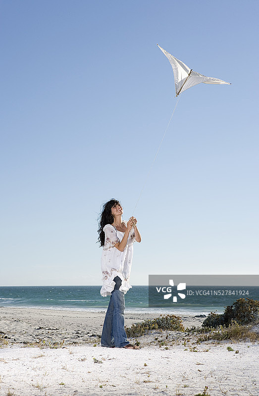 年轻女子在海滩上放风筝图片素材