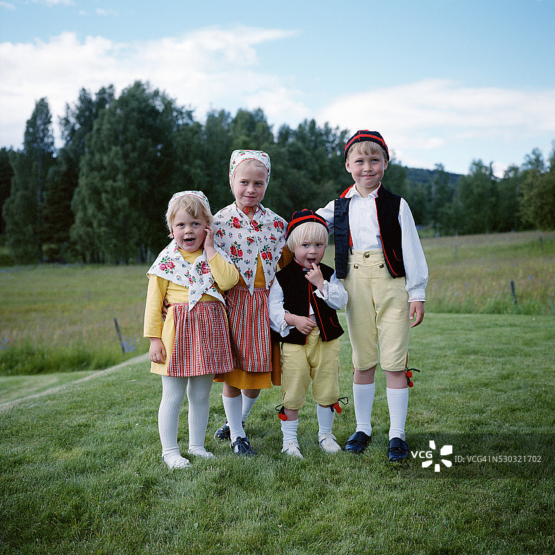 身着传统服饰的儿童站在草地上，肖像图片素材