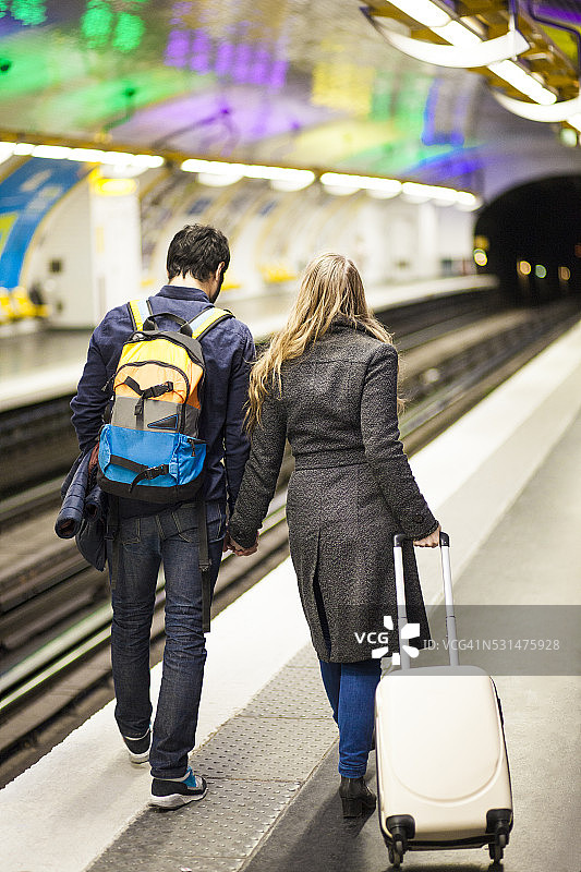 一对年轻的旅行情侣在地铁轨道上散步图片素材