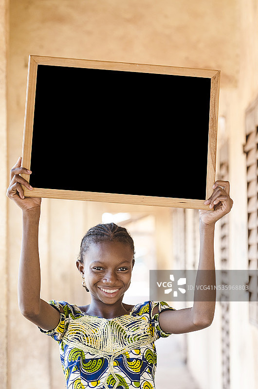 复制空间:非洲少女拿着黑板在学校大楼图片素材