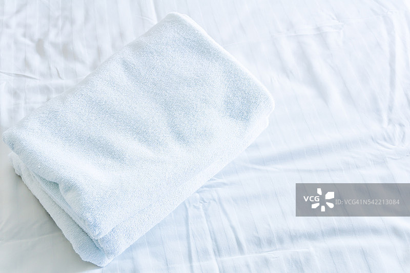 毛巾叠在白色床单上图片素材