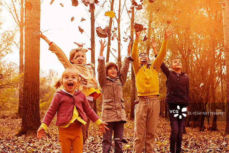 孩子们在秋叶中玩耍。图片素材
