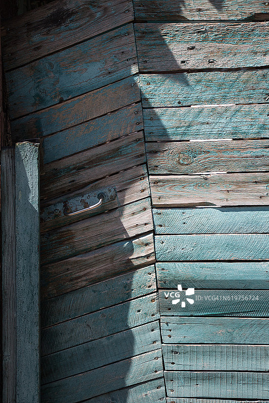 蓝色剥皮木门，由带有金属把手的木板制成图片素材