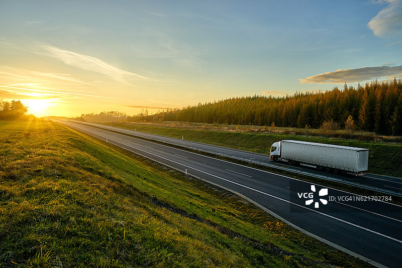 高速公路上载着一辆载货卡车，夕阳下的秋景。图片素材