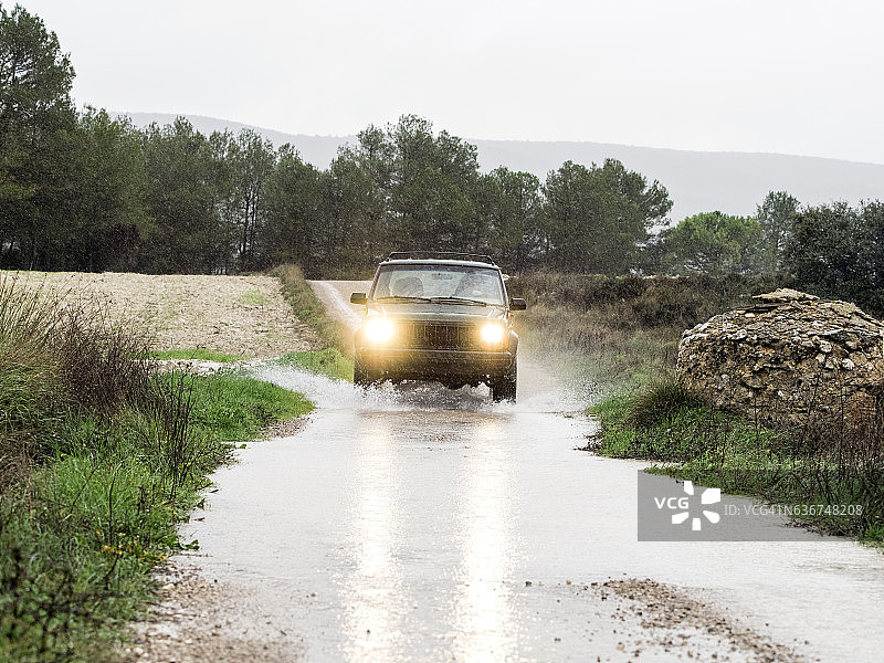 西班牙，四轮驱动汽车在泥泞的道路上溅起大量的雨水。图片素材