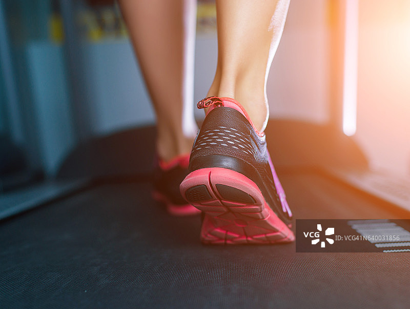 女性肌肉足穿着运动鞋在跑步机上跑步。图片素材