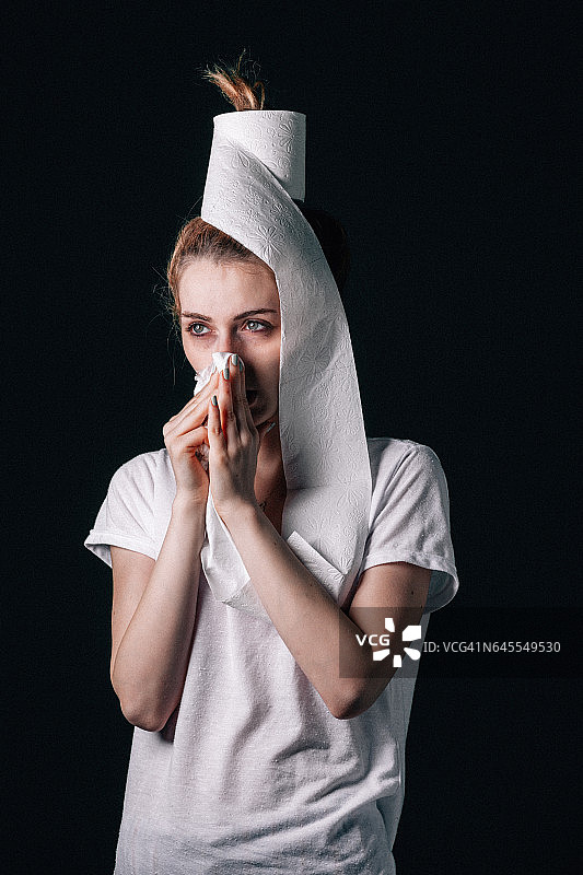 年轻女人得了流感，用手帕擤鼻子图片素材
