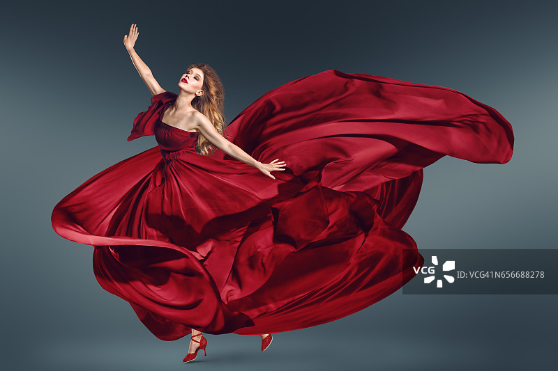 穿着飘动的红色连衣裙跳舞的时尚女子图片素材