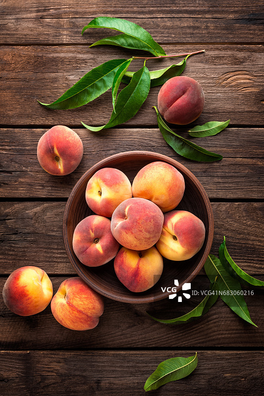 新鲜多汁的桃子与叶片在深色木制乡村背景图片素材