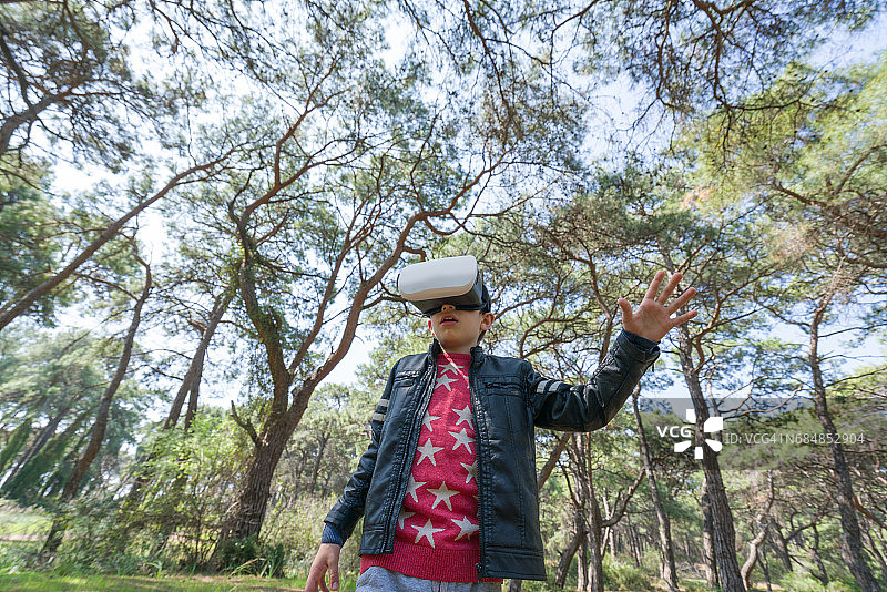 小男孩用虚拟现实头盔玩未来视觉图片素材