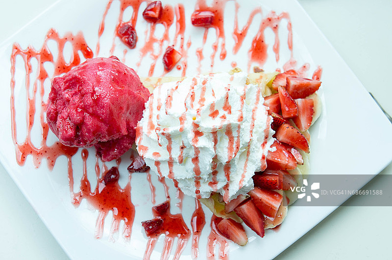 冰淇淋草莓可丽饼甜点在咖啡厅的白色碟木桌上图片素材