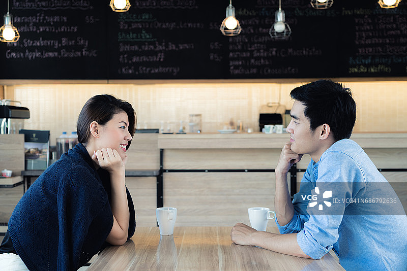 在咖啡馆约会。美丽的亚洲情侣坐在咖啡馆享受咖啡和谈话。爱和浪漫。图片素材