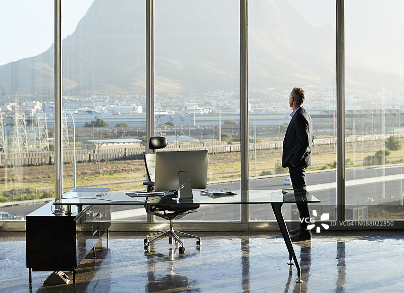 男CEO的肖像在一个大的角落办公室，望着窗外图片素材
