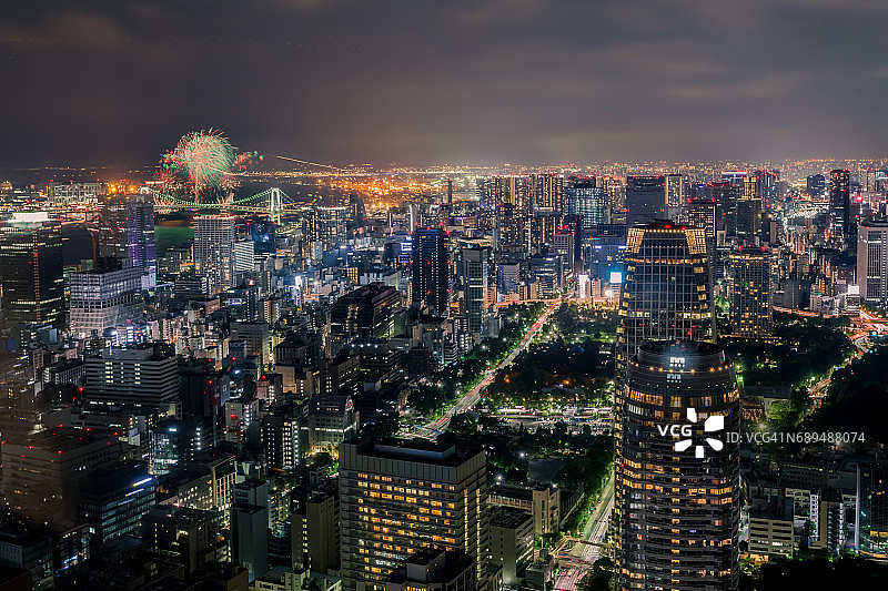 东京城市天际线在夜间与摩天大楼照亮港区，东京，日本。台场彩虹桥烟花活动同时举行。图片素材