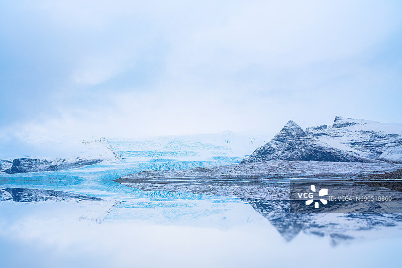 冰岛Jökulsárlón的金字塔状山脉和冰川的倒影。图片素材