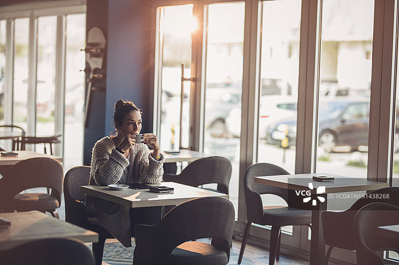 年轻体贴的女人正在咖啡馆喝咖啡。图片素材