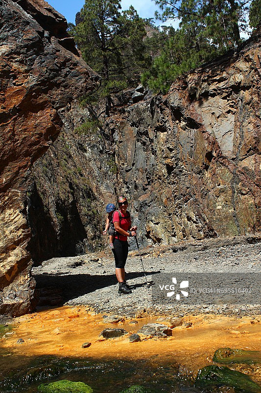 母亲和小女儿在塔布里恩特国家公园的一条有矿泉水的河边徒步旅行。拉帕尔马岛，加那利群岛。西班牙图片素材