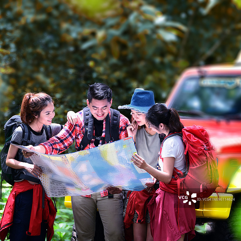 近距离的年轻人徒步旅行者在森林与背包拿着一张地图在农村。营地森林冒险旅行偏远放松概念。图片素材