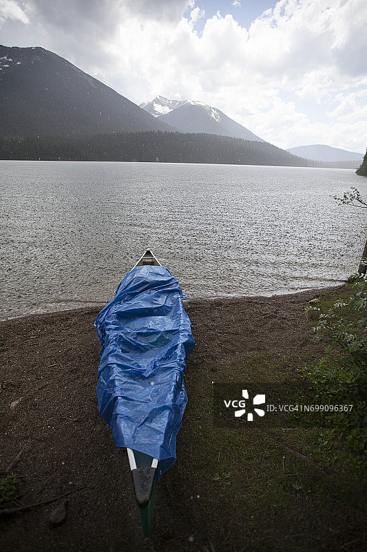下大雨时，独木舟被蓝色防水布覆盖着。图片素材